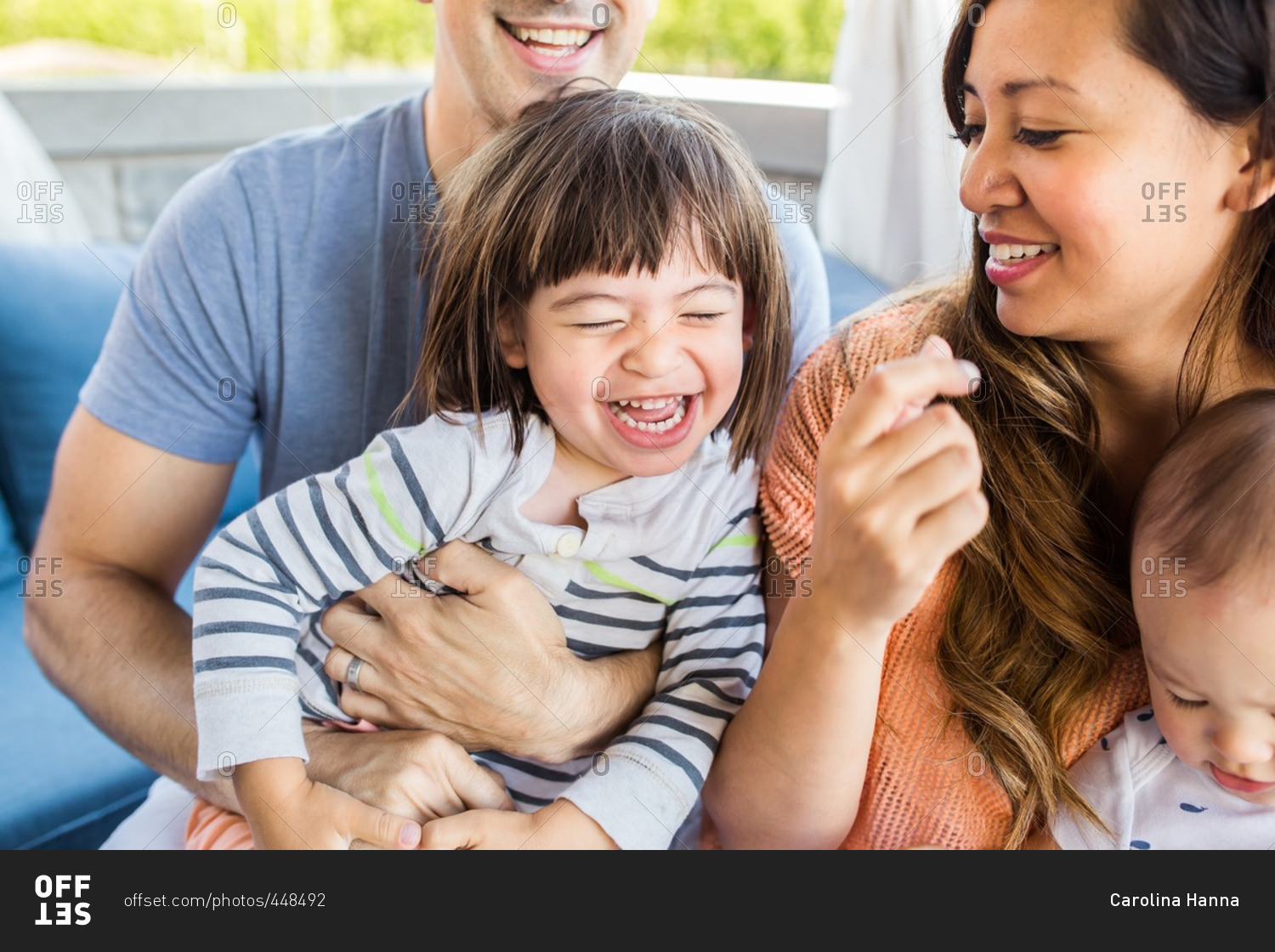 Family sitting on an outdoor couch laughing together