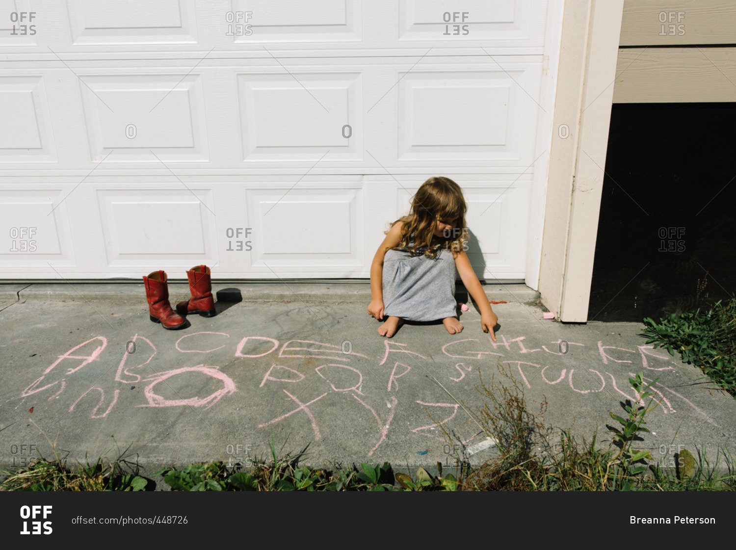 Girl drawing letters with sidewalk chalk