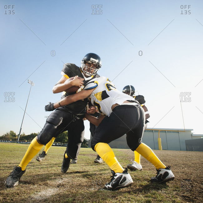 Football player tackling player on football field