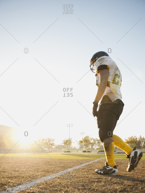 Hispanic football player walking on football field