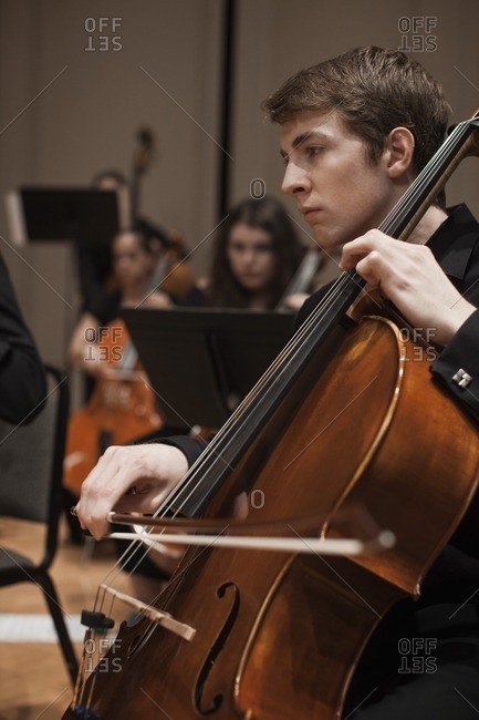 Caucasian man playing cello in orchestra