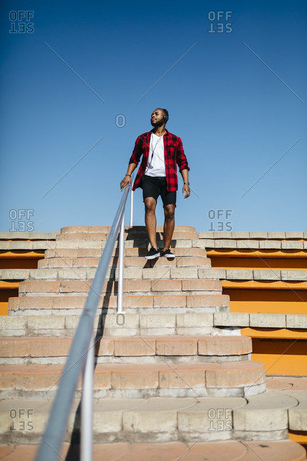 Man on stairs listening to music with headphones outside
