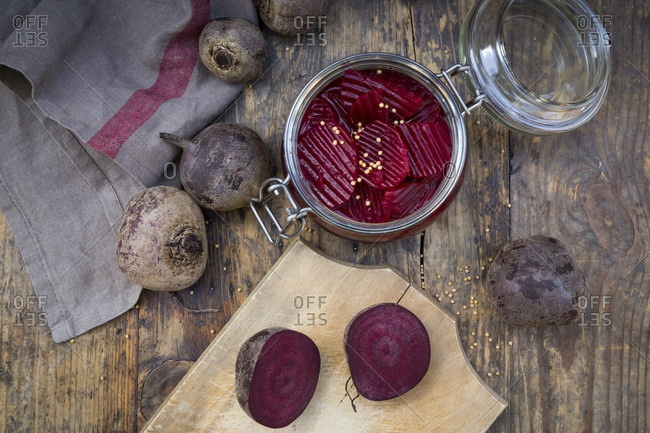 Preserving jar of pickled beetroots and whole and sliced beetroots on wood