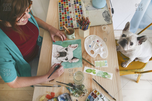 Artist painting an aquarelle of her French bulldog in her studio