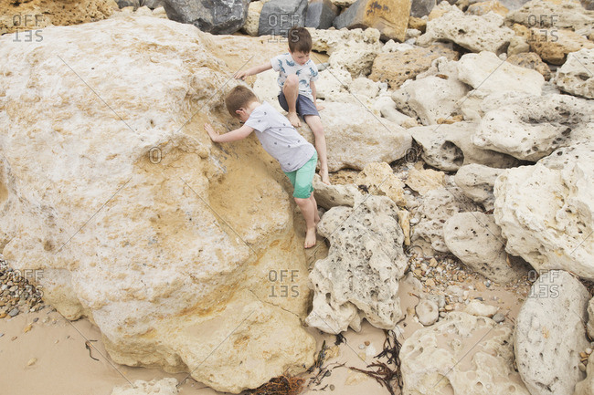 Two boys playing on wave eroded rocks on beach