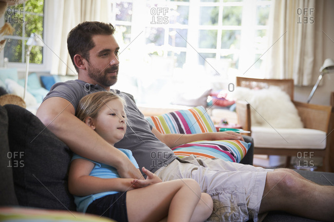 Father And Daughter Sitting On Sofa Watching Tv Together Stock