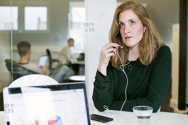 Sweden, Woman with headphones working at desk