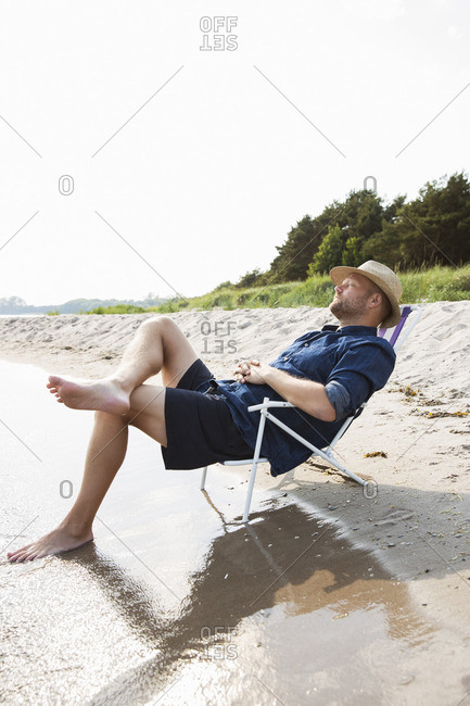 Sweden, Gotland, Mature man sitting on deckchair at seashore