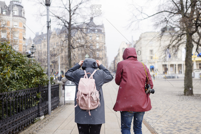 Sweden, Stockholm, Young couple walking through city in falling snow