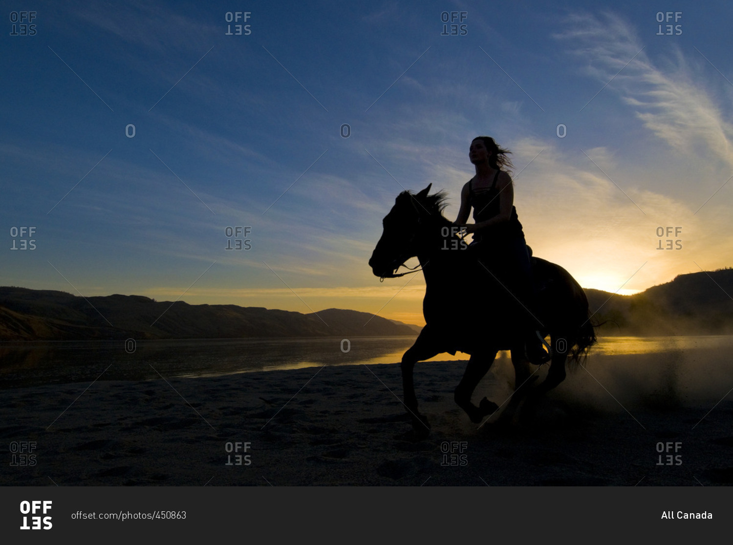 Silhouette of a young women riding her horse after sunset, along the banks of the Thompson River, just west of Kamloops, British Columbia, Canada
