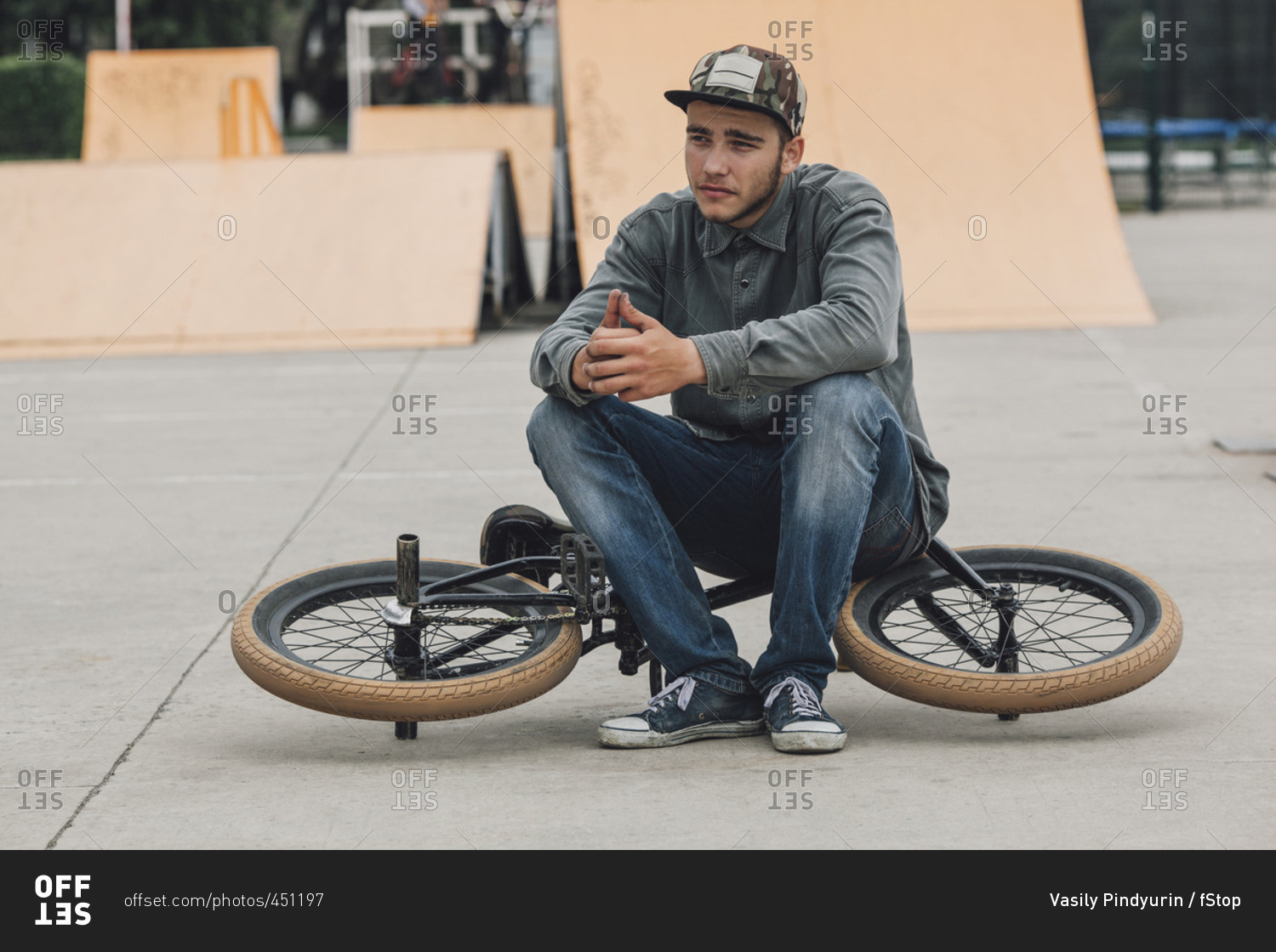 Teenage boy contemplating while sitting on bicycle at skateboard park