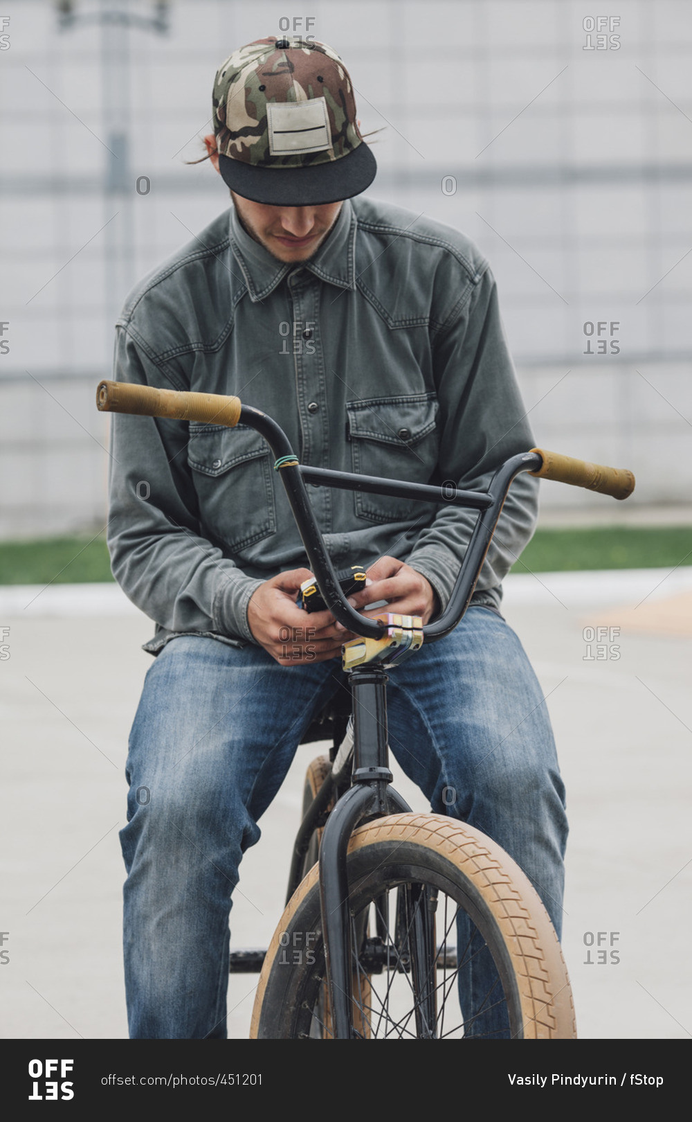 Teenager using phone while sitting on bicycle at skateboard park
