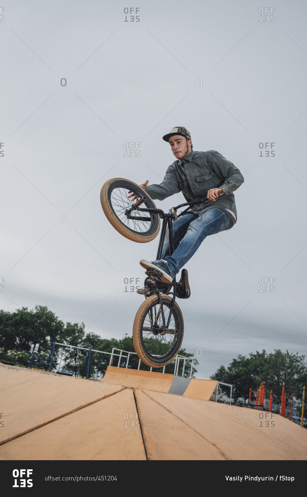 Teenager performing stunt at skateboard park against sky