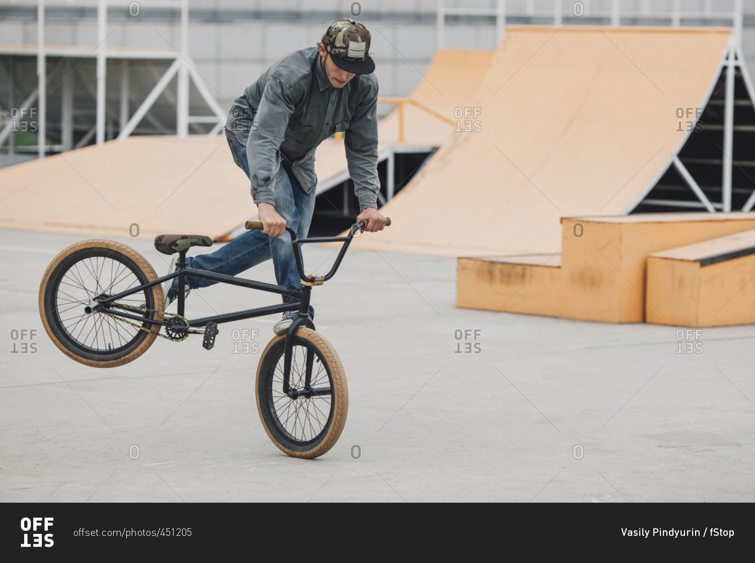 Teenager performing wheelie with bicycle at skateboard park