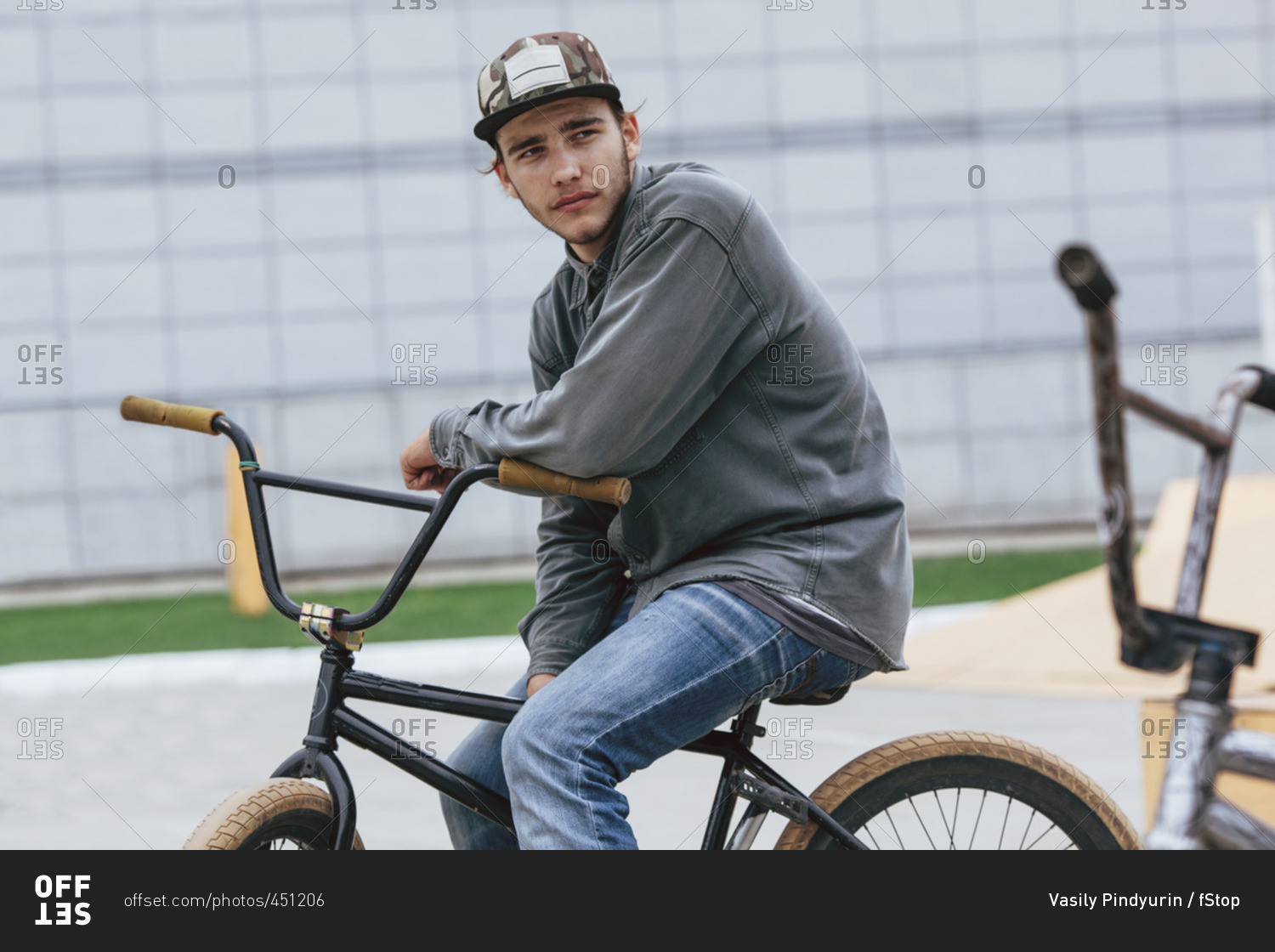 Thoughtful teenage boy sitting on bicycle at skateboard park