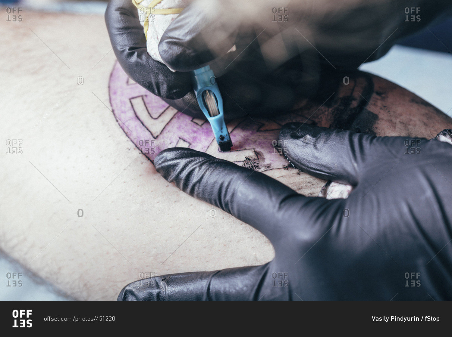 Artist tattooing design on human skin at studio