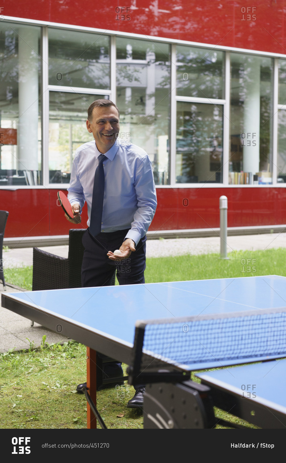 Happy businessman playing table tennis at creative office