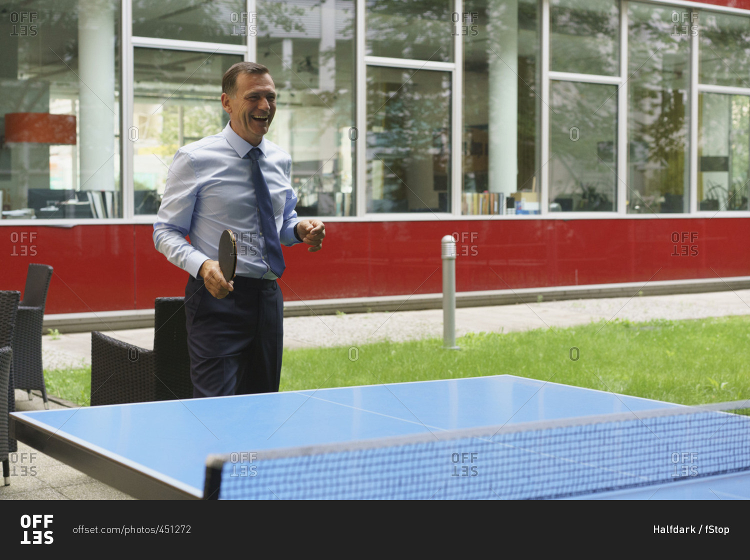 Cheerful businessman playing table tennis at creative office