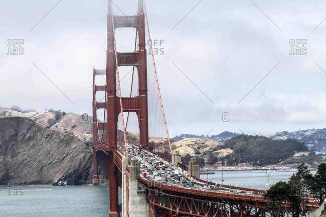 View of Golden Gate Bridge over bay of water against mountain during foggy weather