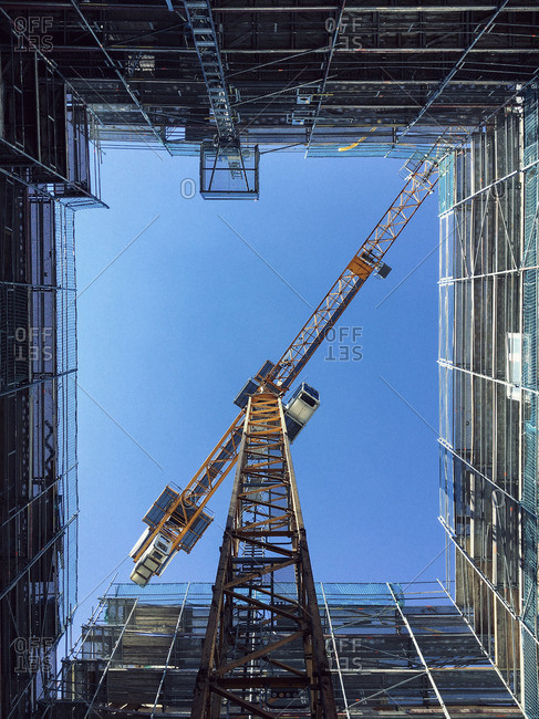 Directly below shot of crane amidst glass building against clear blue sky