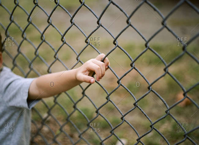 Boy's hand holding on fence