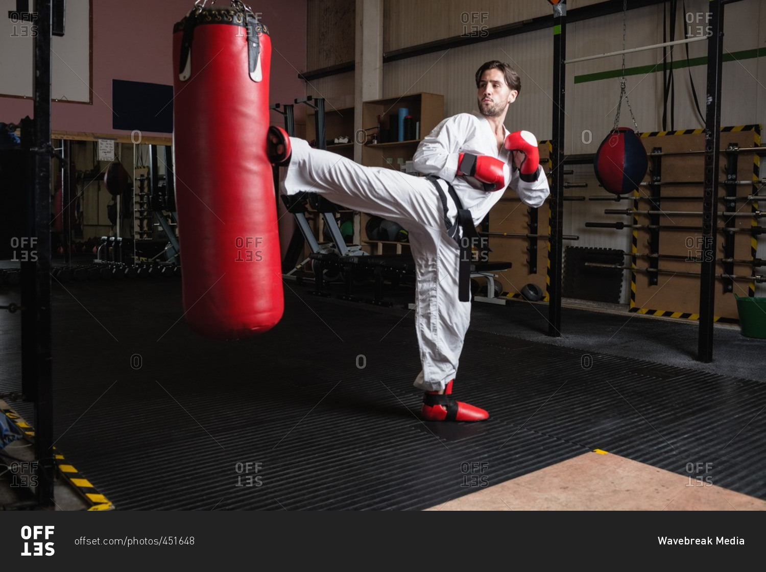 Man practicing karate with punching bag in fitness studio