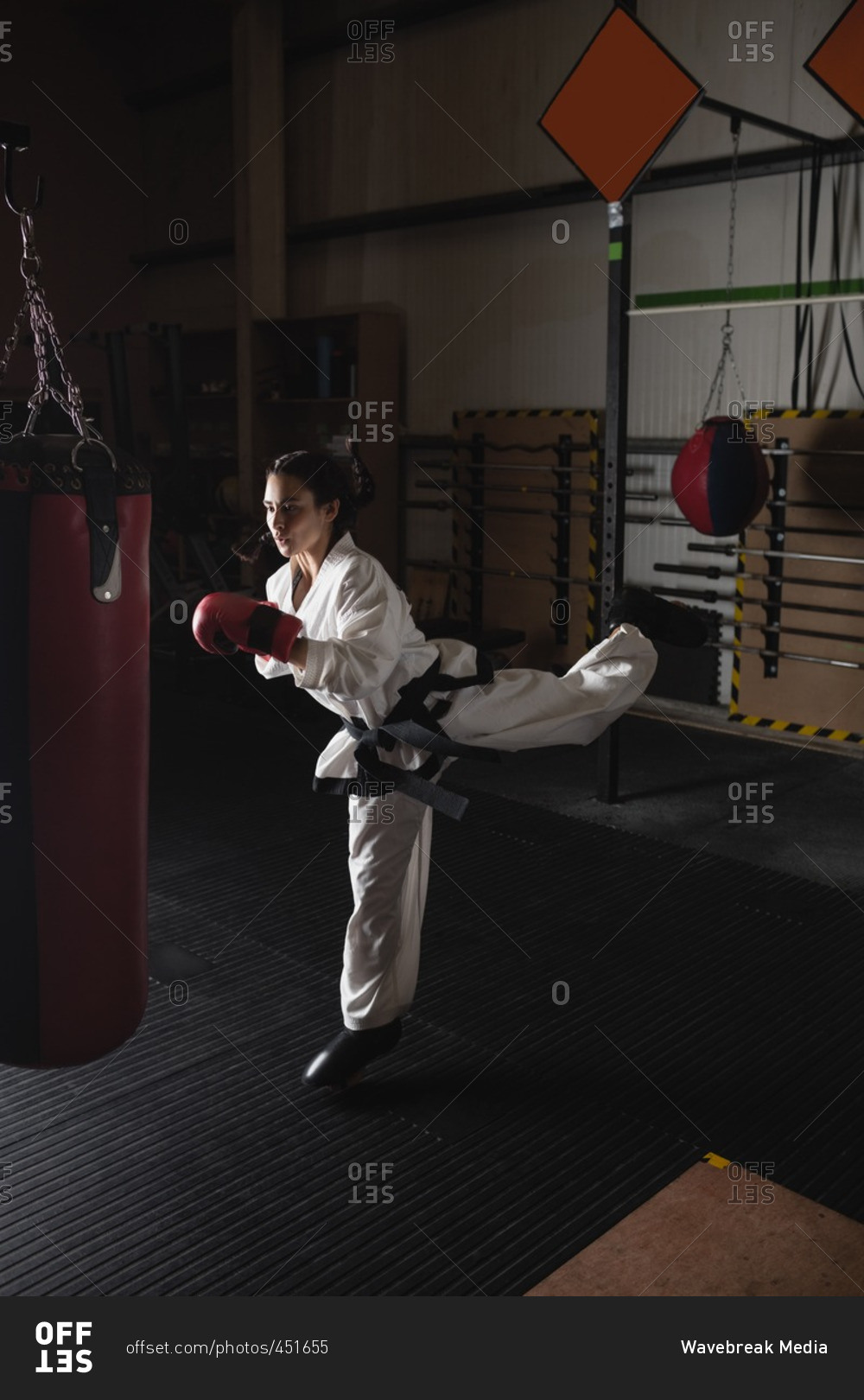 Woman practicing karate with punching bag in fitness studio