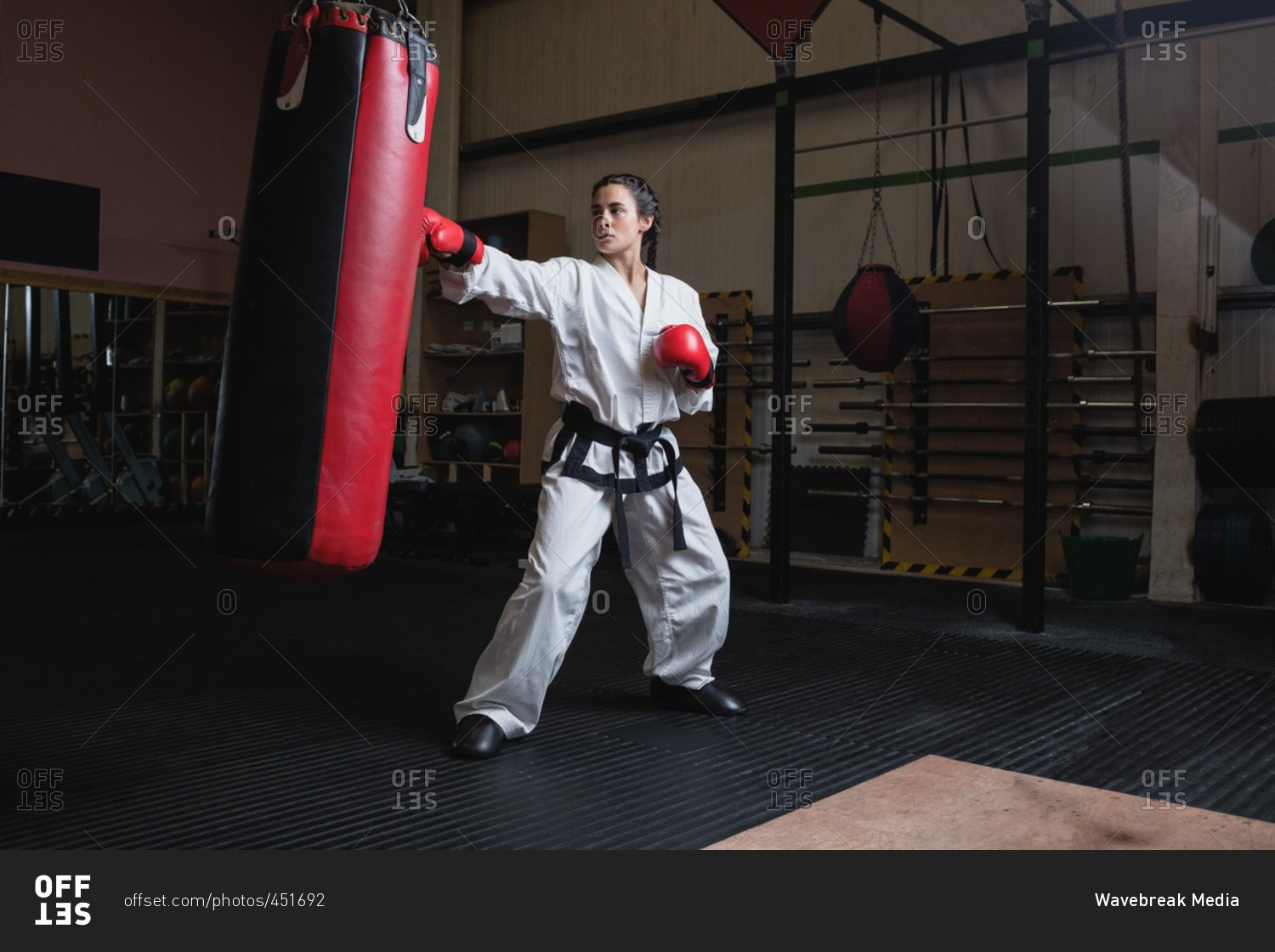 Woman practicing karate with punching bag in fitness studio