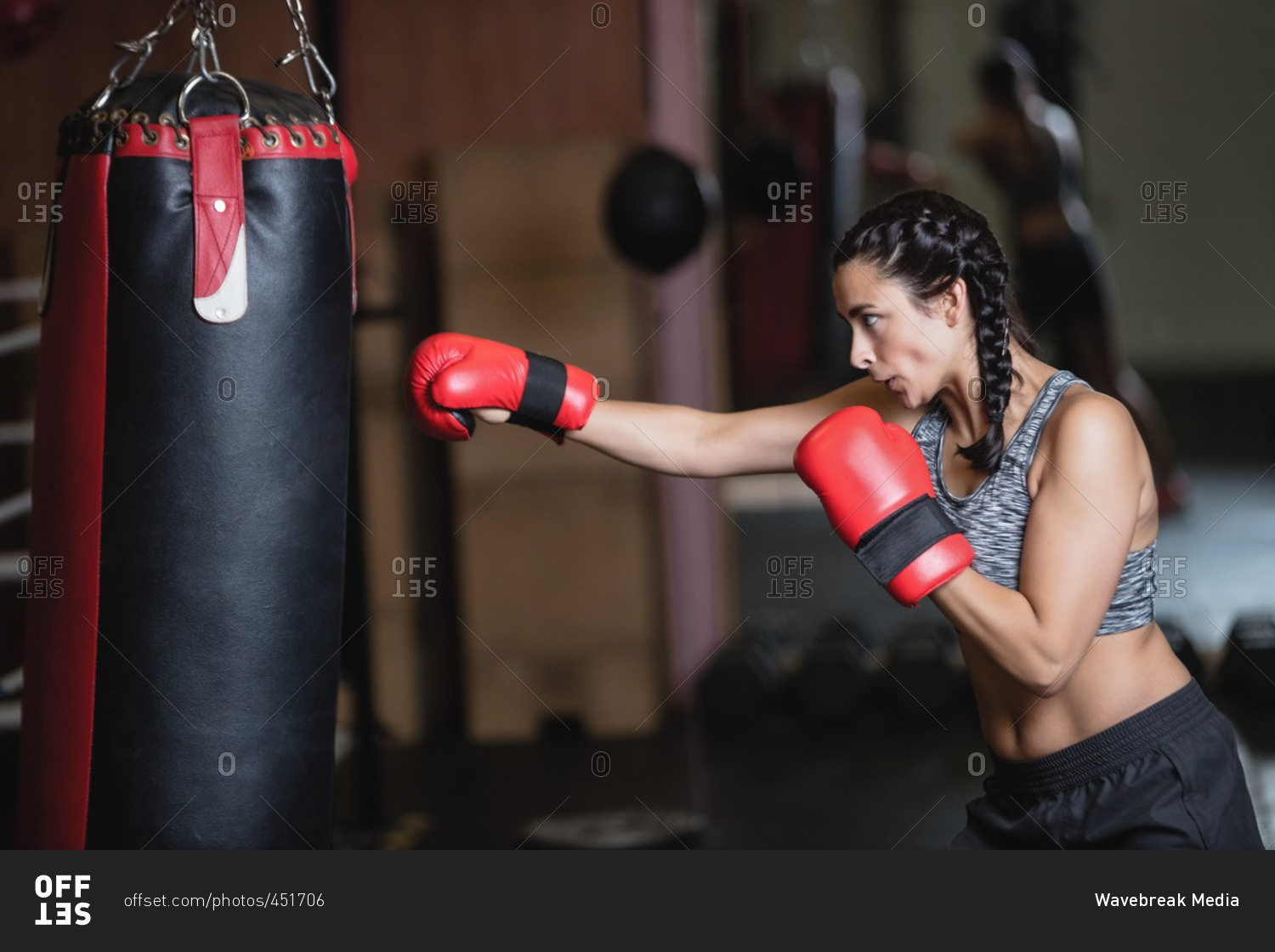 Female boxer practicing boxing with punching bag in fitness studio