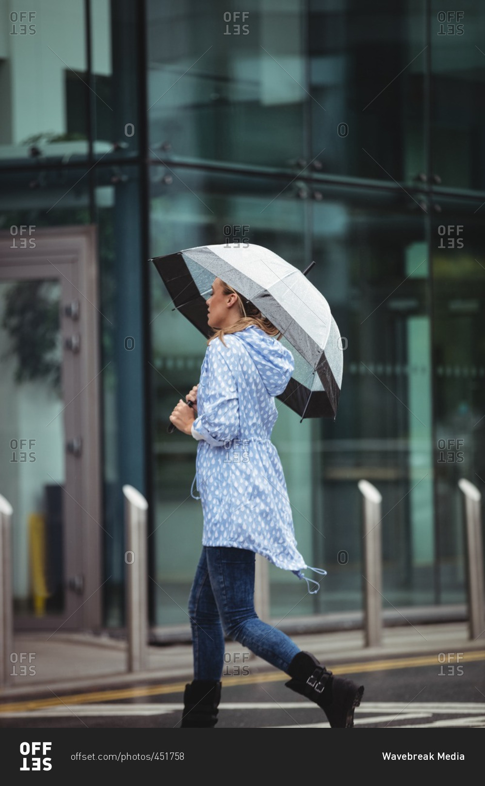 Beautiful woman holding umbrella and walking on street during rainy season
