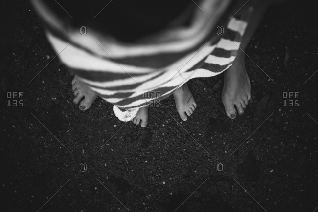 Little boy's feet standing between his mother's feet