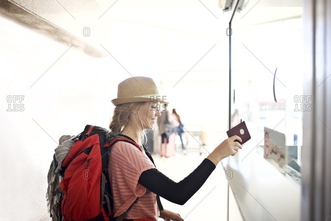 Young woman handing passport to customs agent