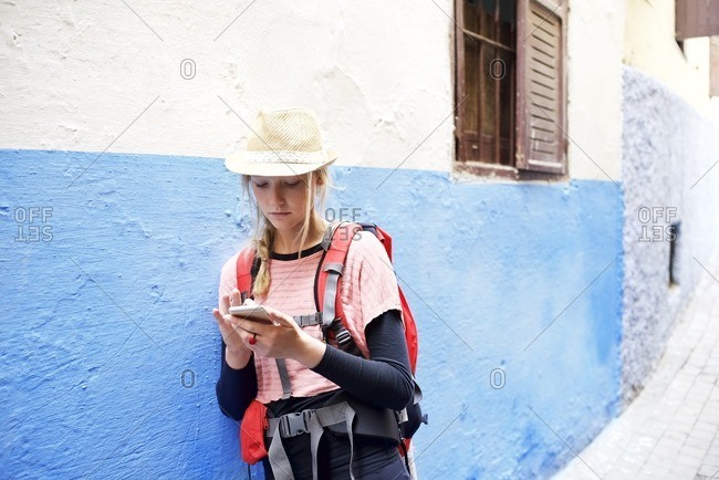 Young woman using smartphone in alley