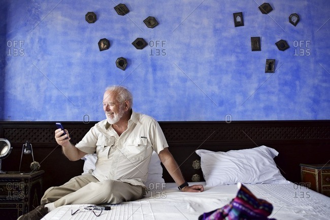 Senior man texting on cell phone in hotel room