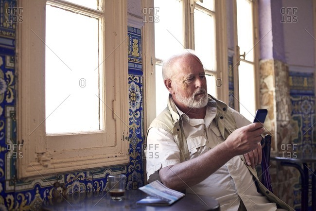 Senior man checking his phone in cafe