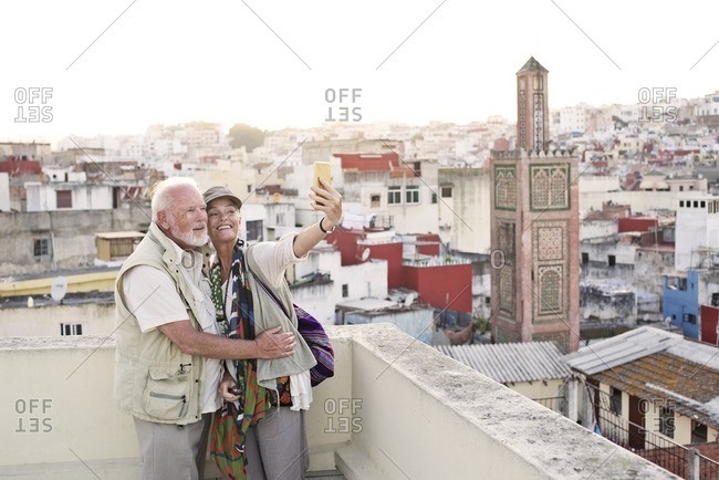 Senior couple taking a selfie on terrace at sunset