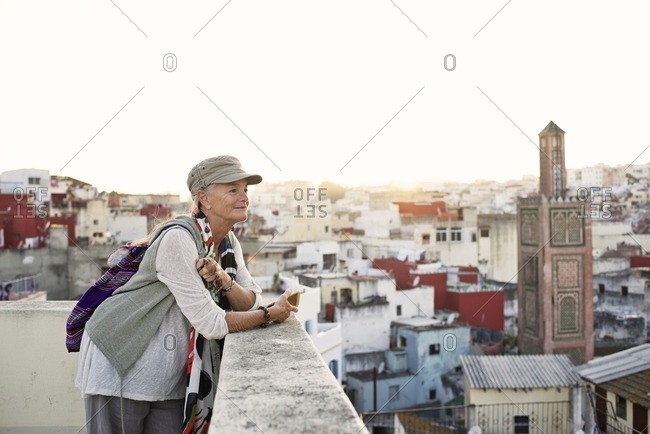 Senior woman overlooking Middle Eastern city at sunset