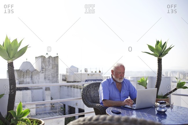 Senior man using laptop on terrace