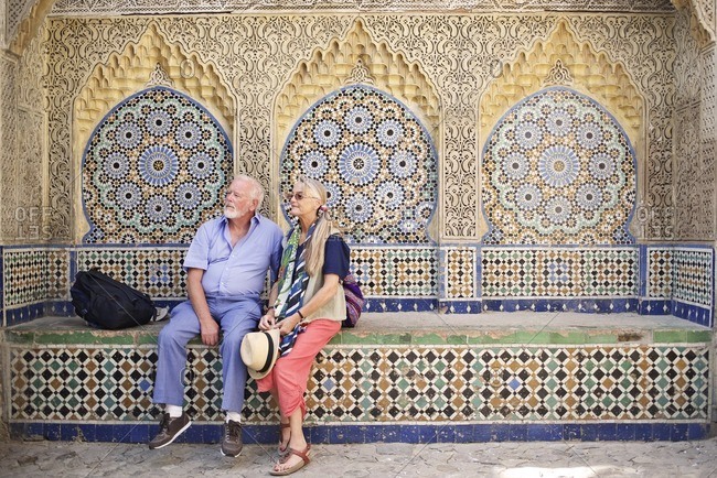 Senior couple sitting on colorful tiled bench