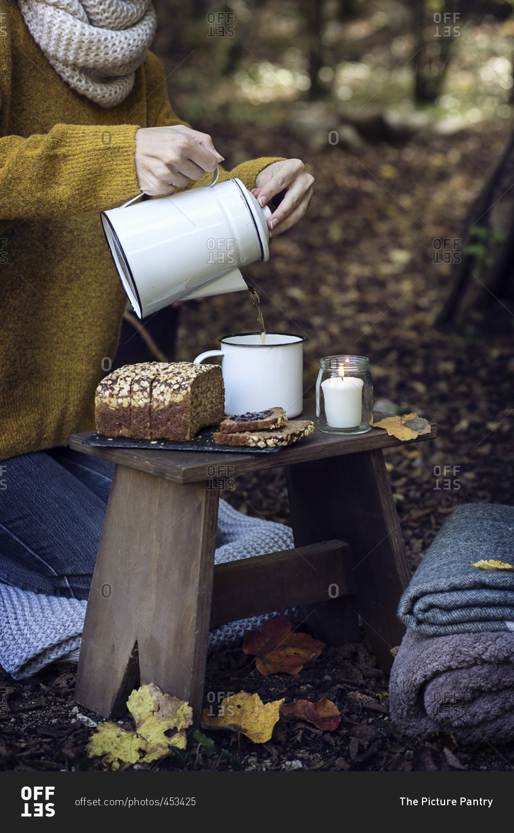 Woman pouring tea in a cup during a picnic in the woods
