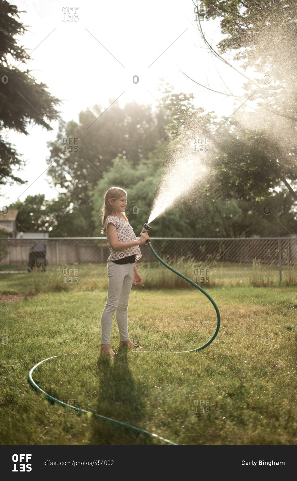 Girl spraying hose into the air in her backyard