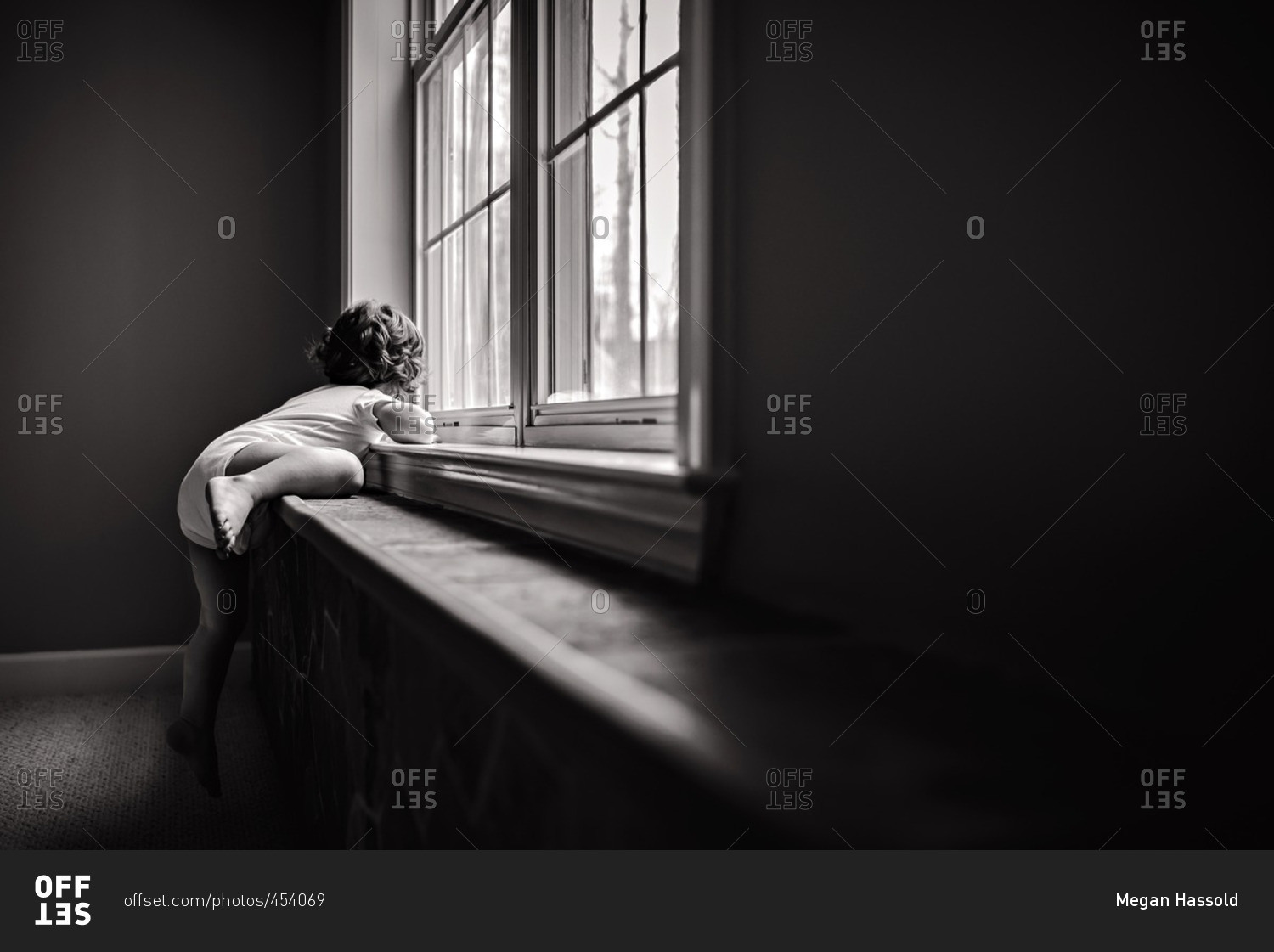 Toddler climbing onto a window stock photo OFFSET