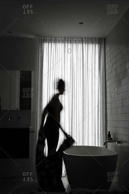 Woman in silhouette by bath tub