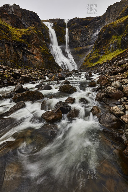 Waterfall flowing down rocky hill in Iceland