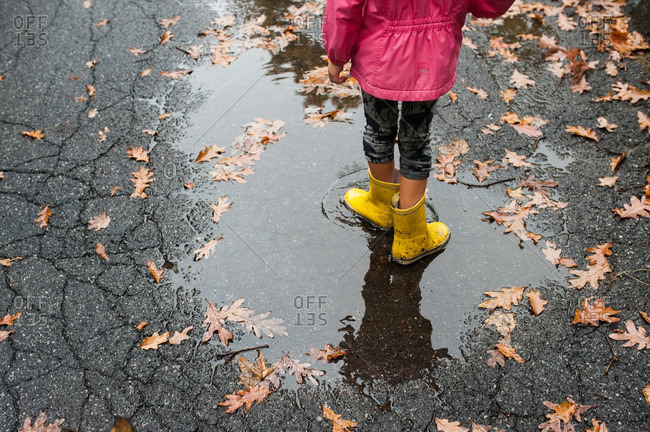 Girl wearing rubber boots stepping in a puddle