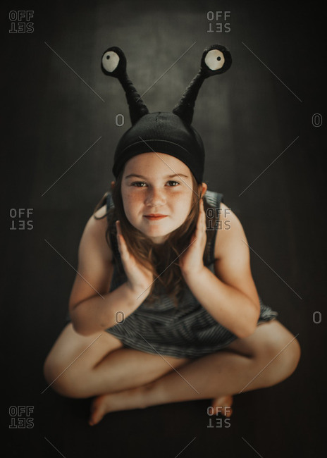 Portrait of girl in an alien hat sitting cross-legged