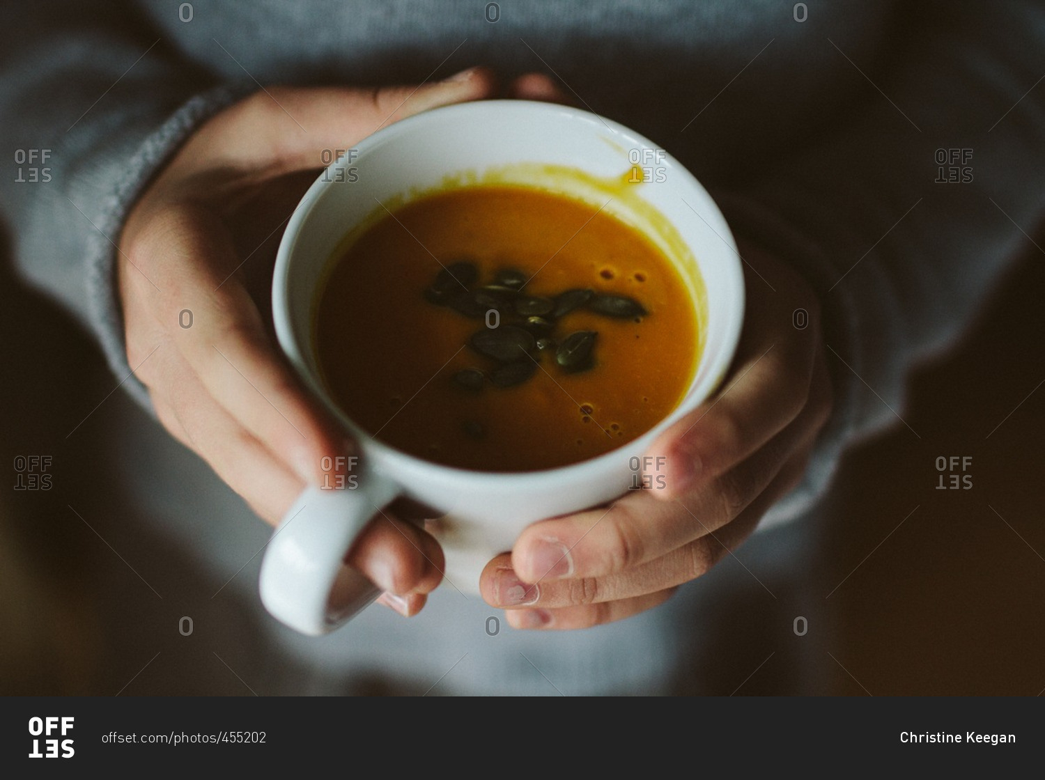 Hands holding a cup of pumpkin soup
