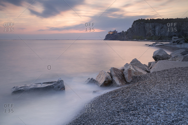 The Duino castle at sunset photographed from Porto Piccolo's beach in Sistiana, Trieste, Italy