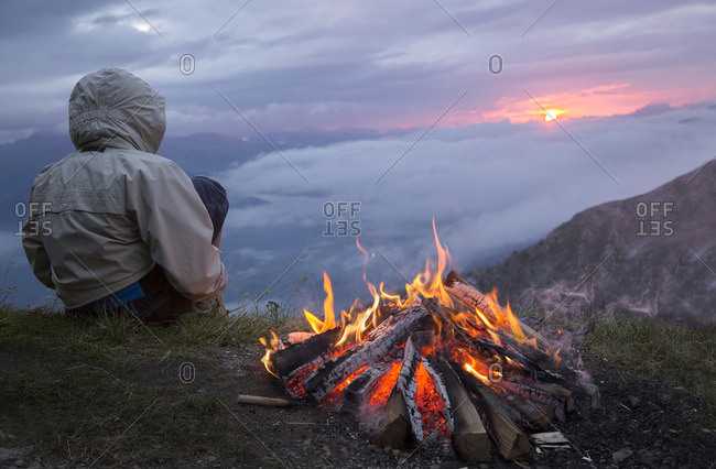 Young trekker can enjoy the sunrise on the Sesto Dolomites from Mount Elmo around a fire, Bolzano district, South Tyrol, Trentino Alto Adige, Italy