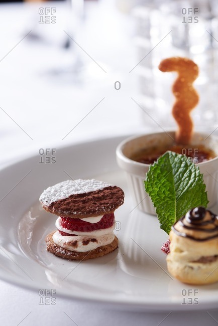 Four small dessert bites consisting of an apricot tart, mini cream puff, black and white cookie and mini creme brulee served on a single plate in a traditional French restaurant in Incline Village in Lake Tahoe, California.